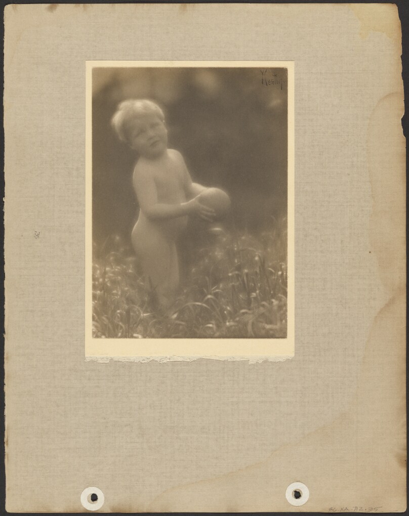 [Brett Weston, nude, standing in a field, holding a ball]