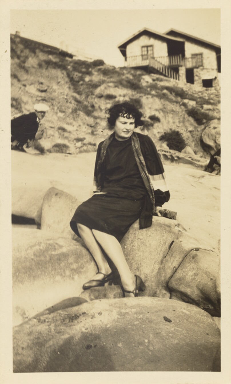 [Woman sitting on rocks at beach]