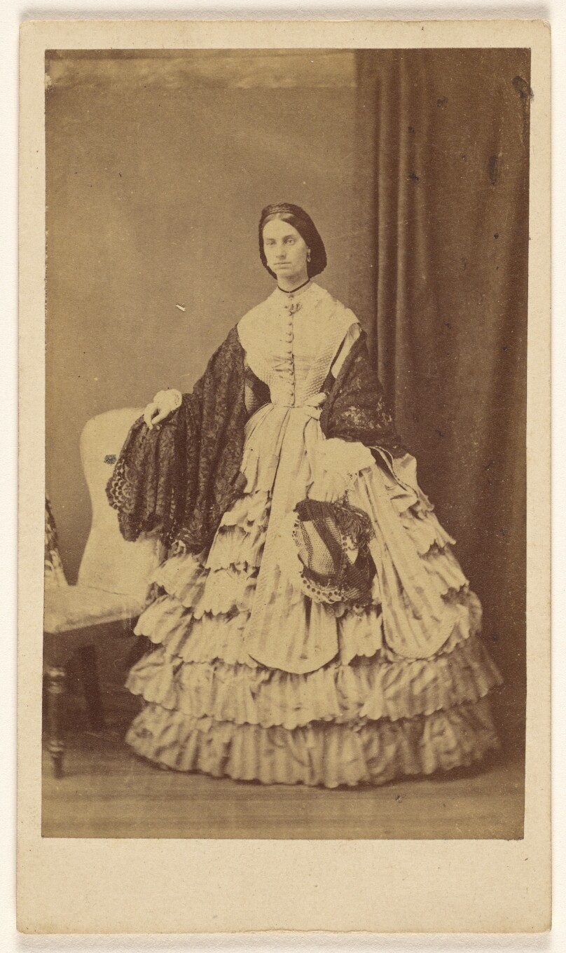 [Woman in long white dress and shawl, standing]