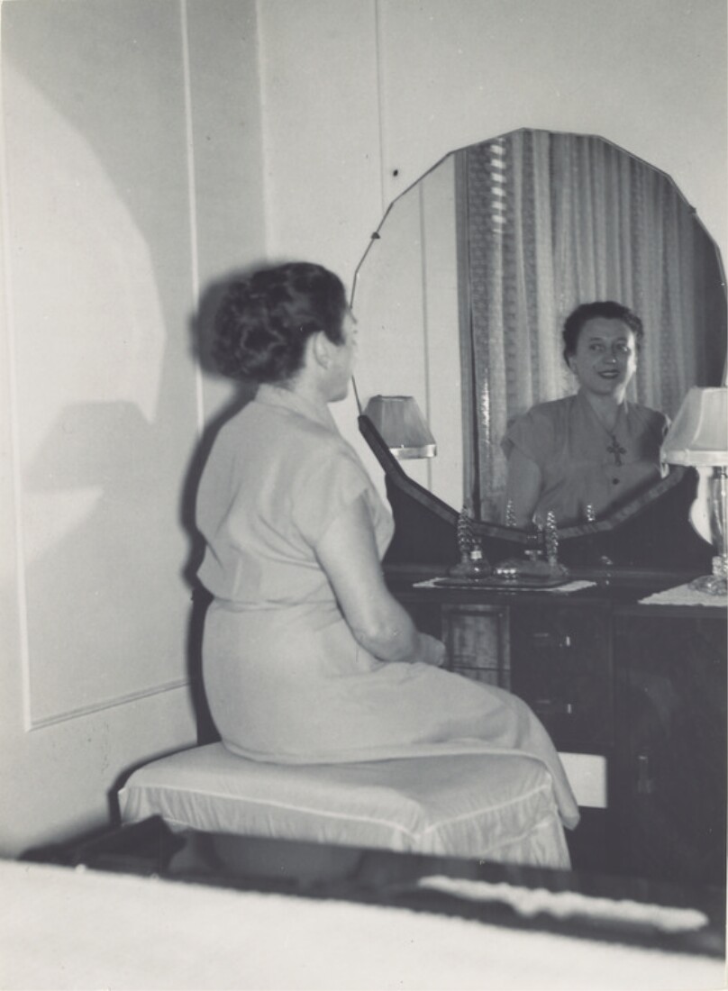 [Woman seated at vanity]