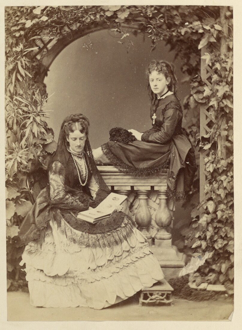 [Two young women under ivied arch]