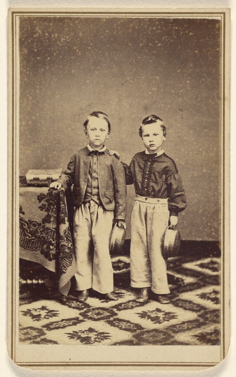 [Two unidentified boys, each holding a hat, standing]