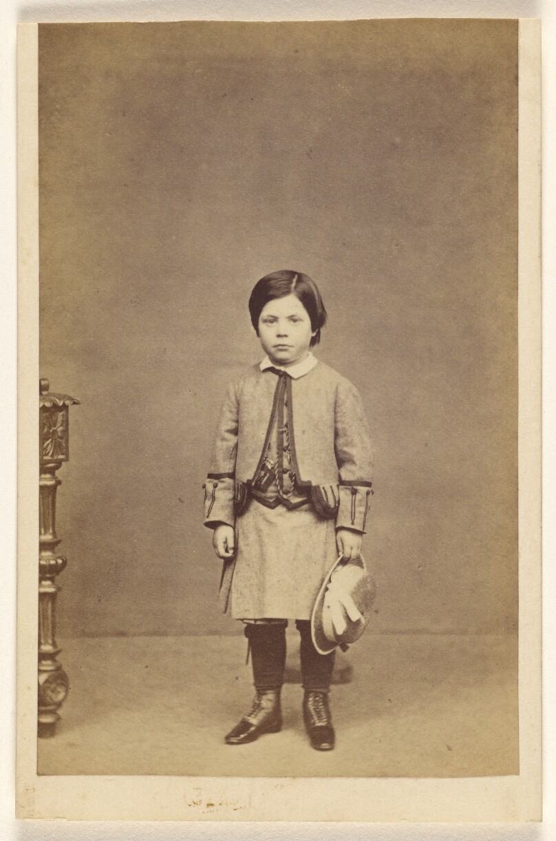 [Unidentified little girl standing, holding hat]