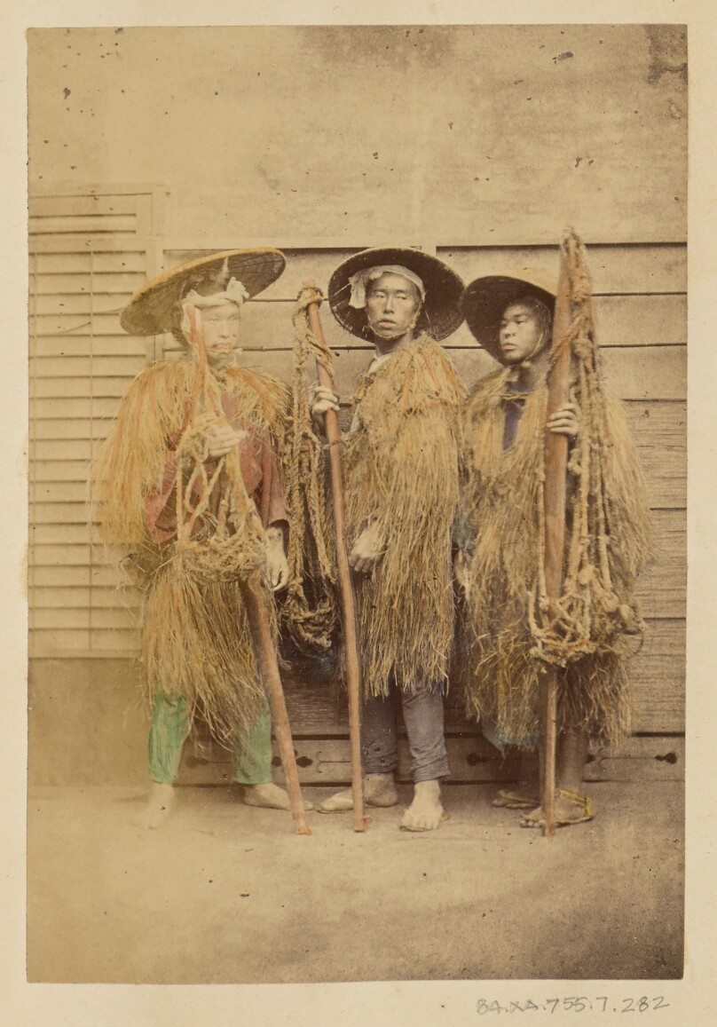 [Three Japanese men in grass robes and wide-brimmed hats]