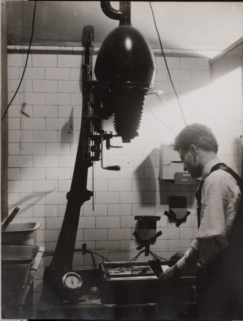 [Man uses a photographic enlarger in a darkroom]
