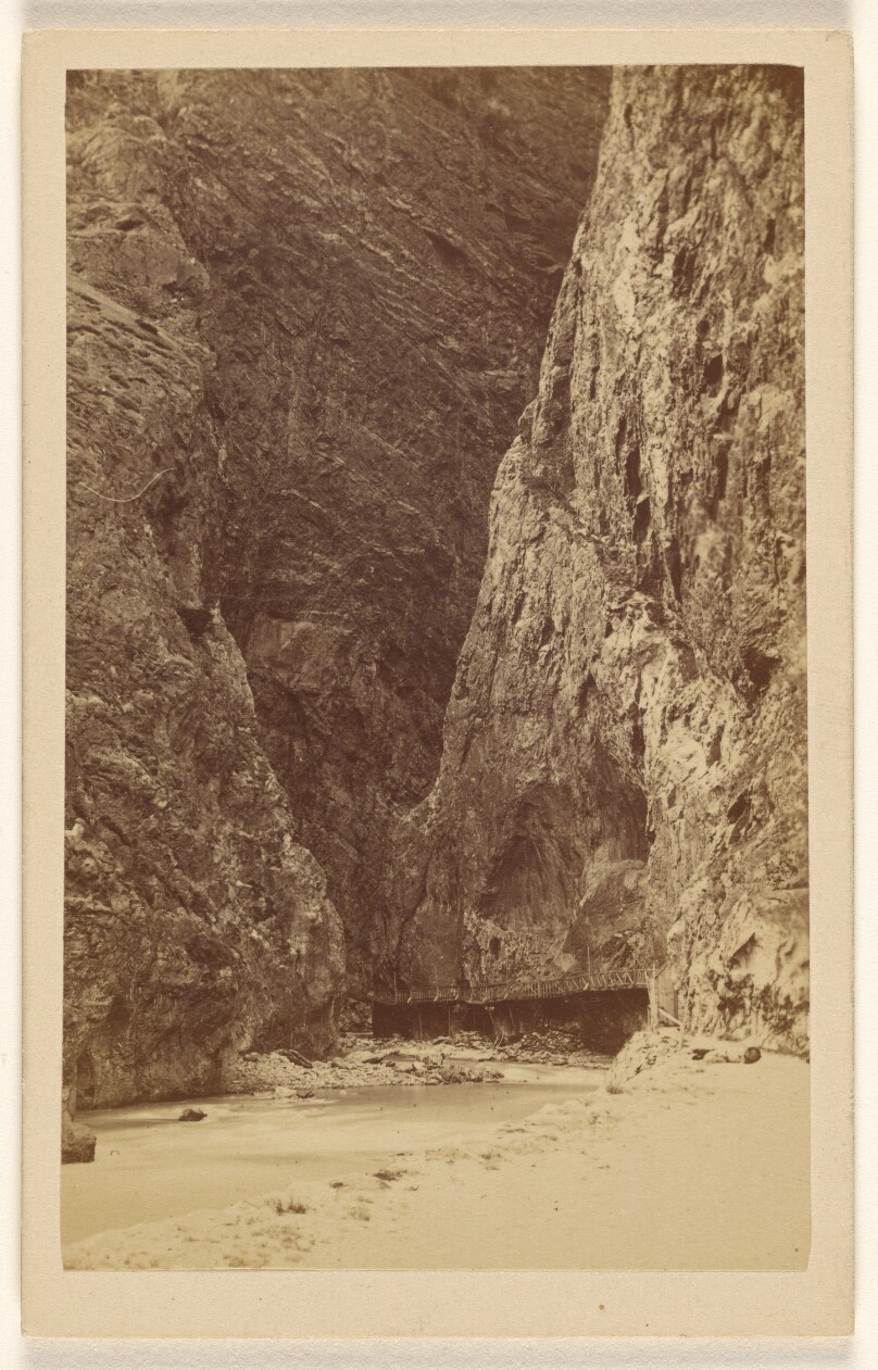 [View of an enclosed mountain canyon with river and bridge]