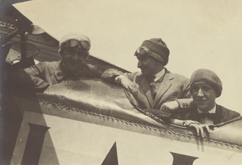 [Three men in the cockpit of an airplane]