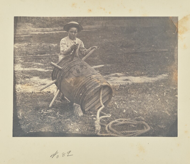[Child leaning against a barrel anchor]