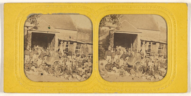 [Group of firemen posed outside in front of station with wagon]