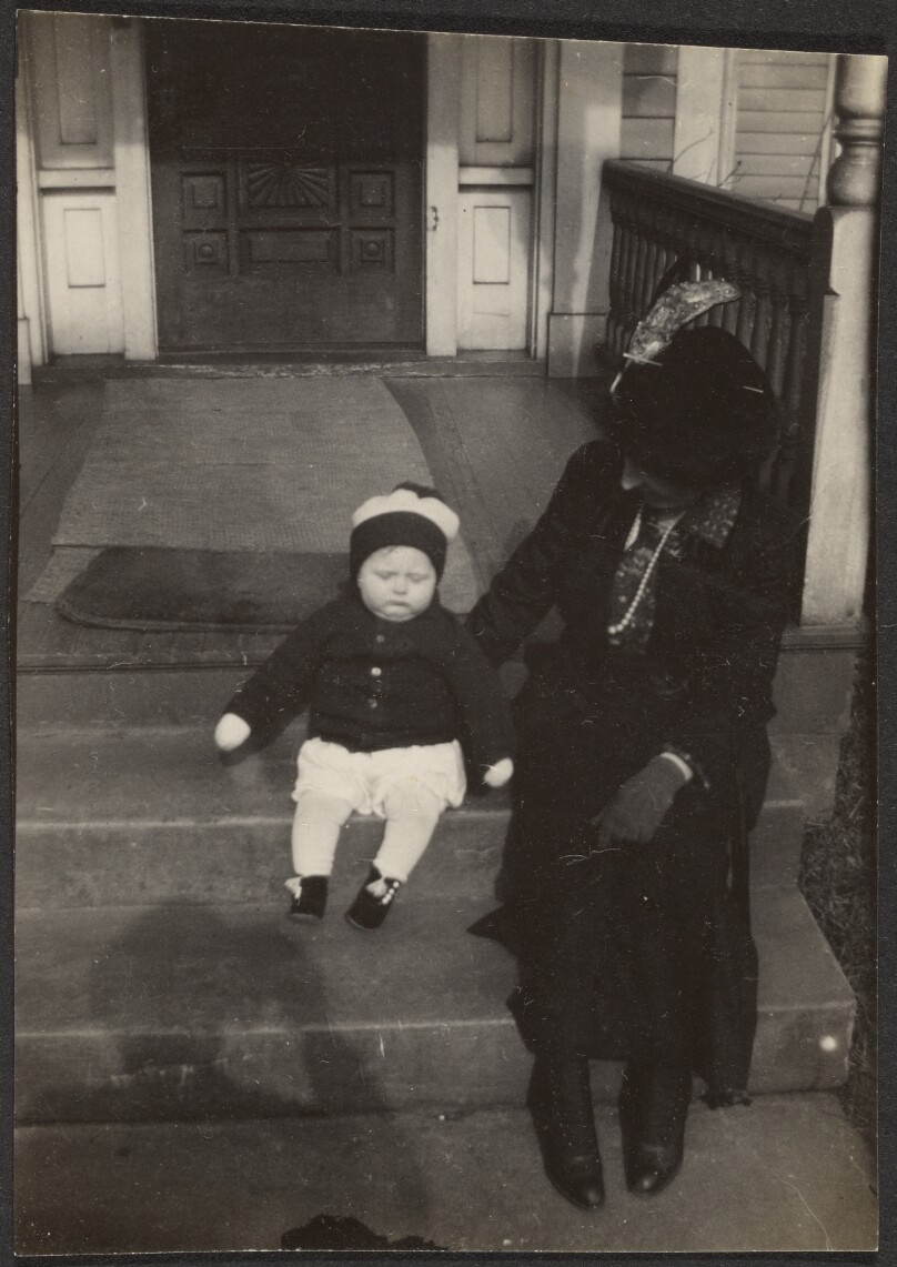 [Woman and child sitting on front steps]