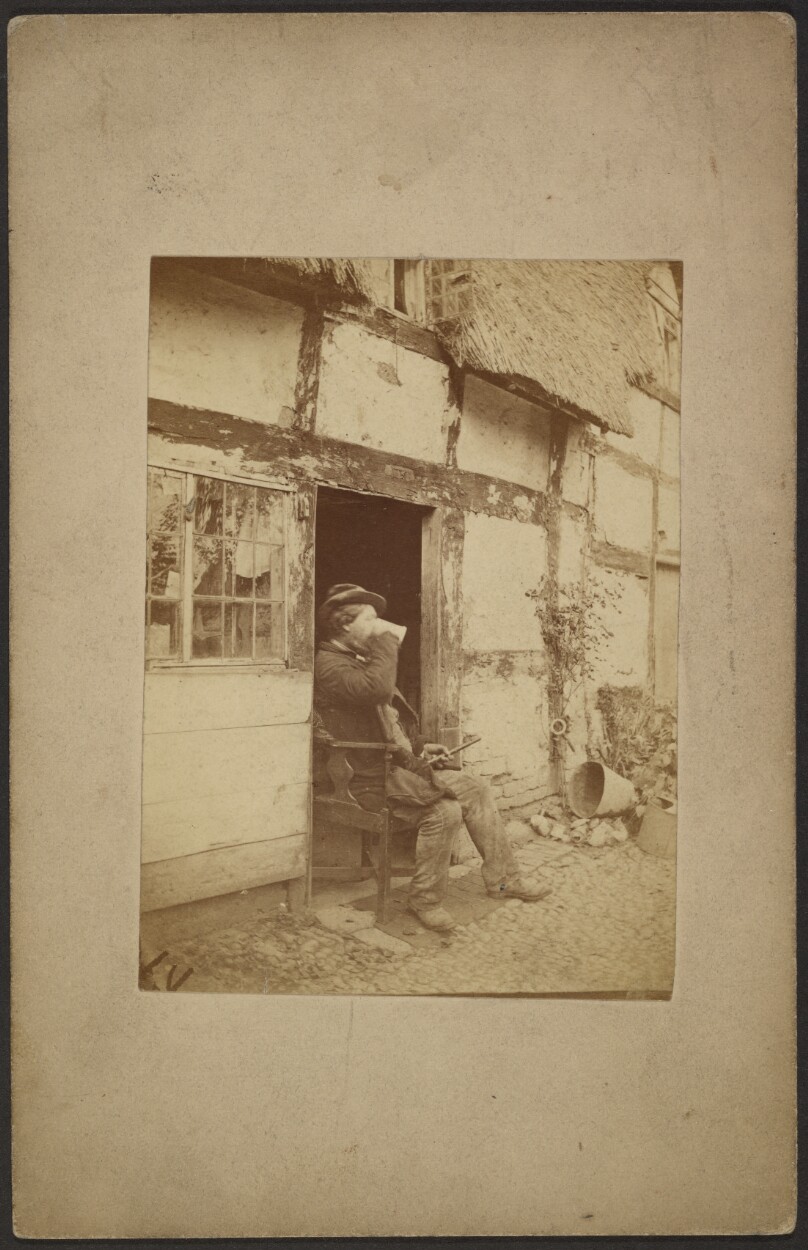 [Seated man drinking from mug in open doorway]