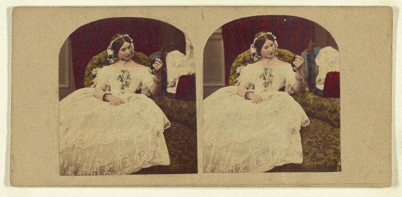 [Woman seated in enlongated chair admiring herself in a hand mirror]