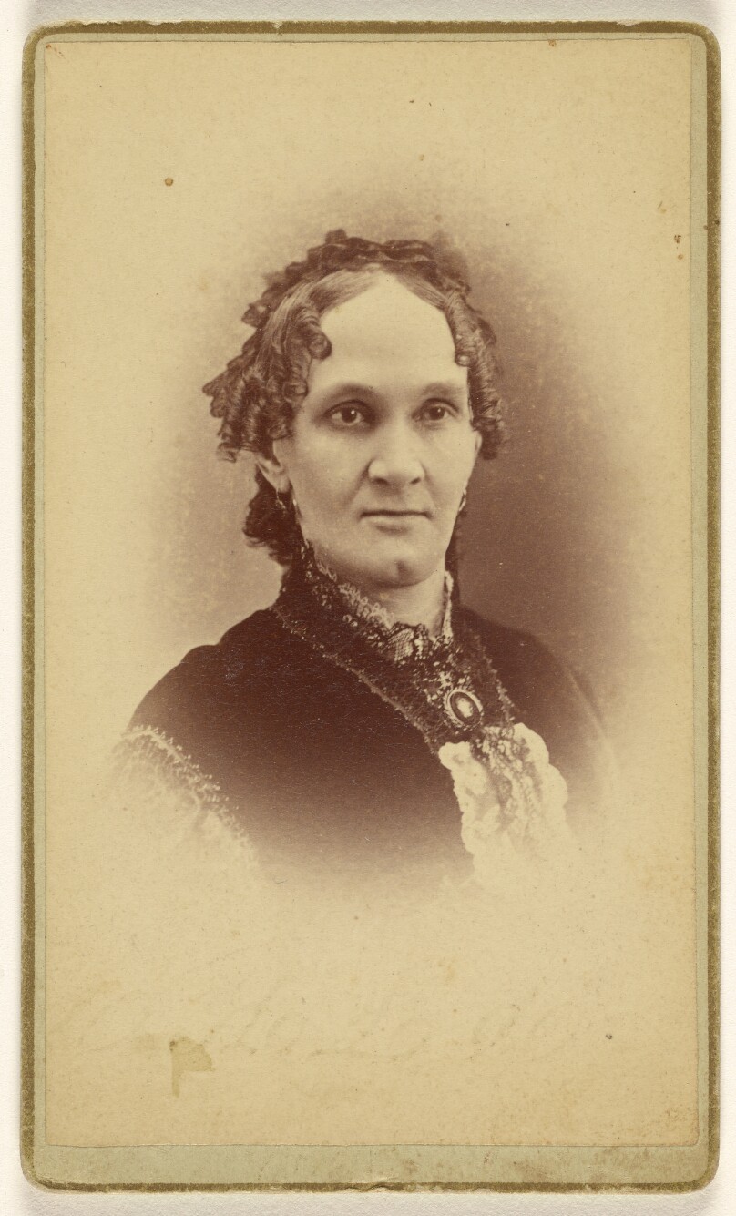 [Unidentified woman with short curly hair, wearing a cameo, printed in vignette-style]