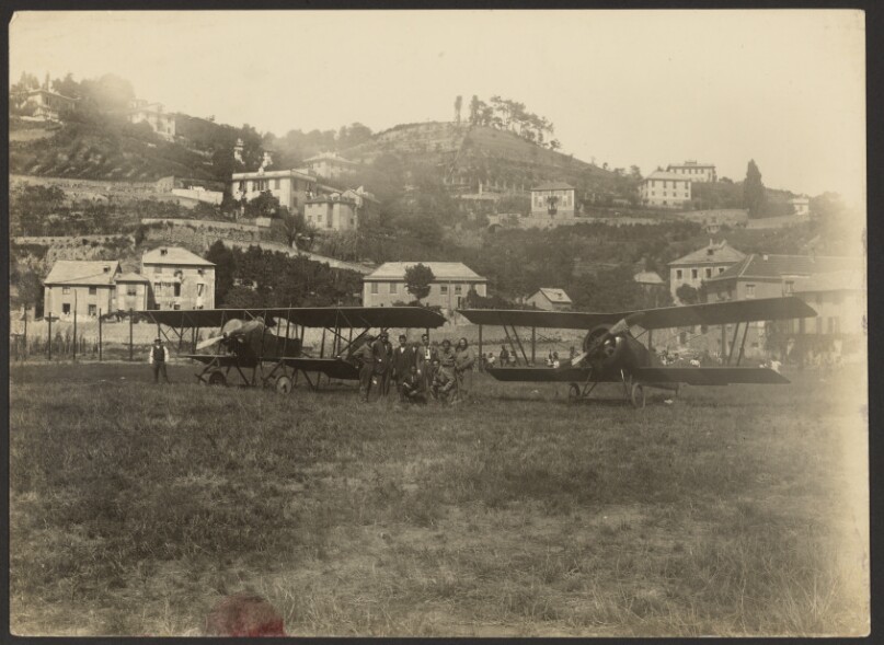 [Group portrait between two airplanes]
