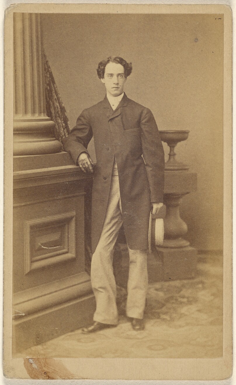 [Unidentified man wearing gloves, holding a straw hat in his left hand, standing]