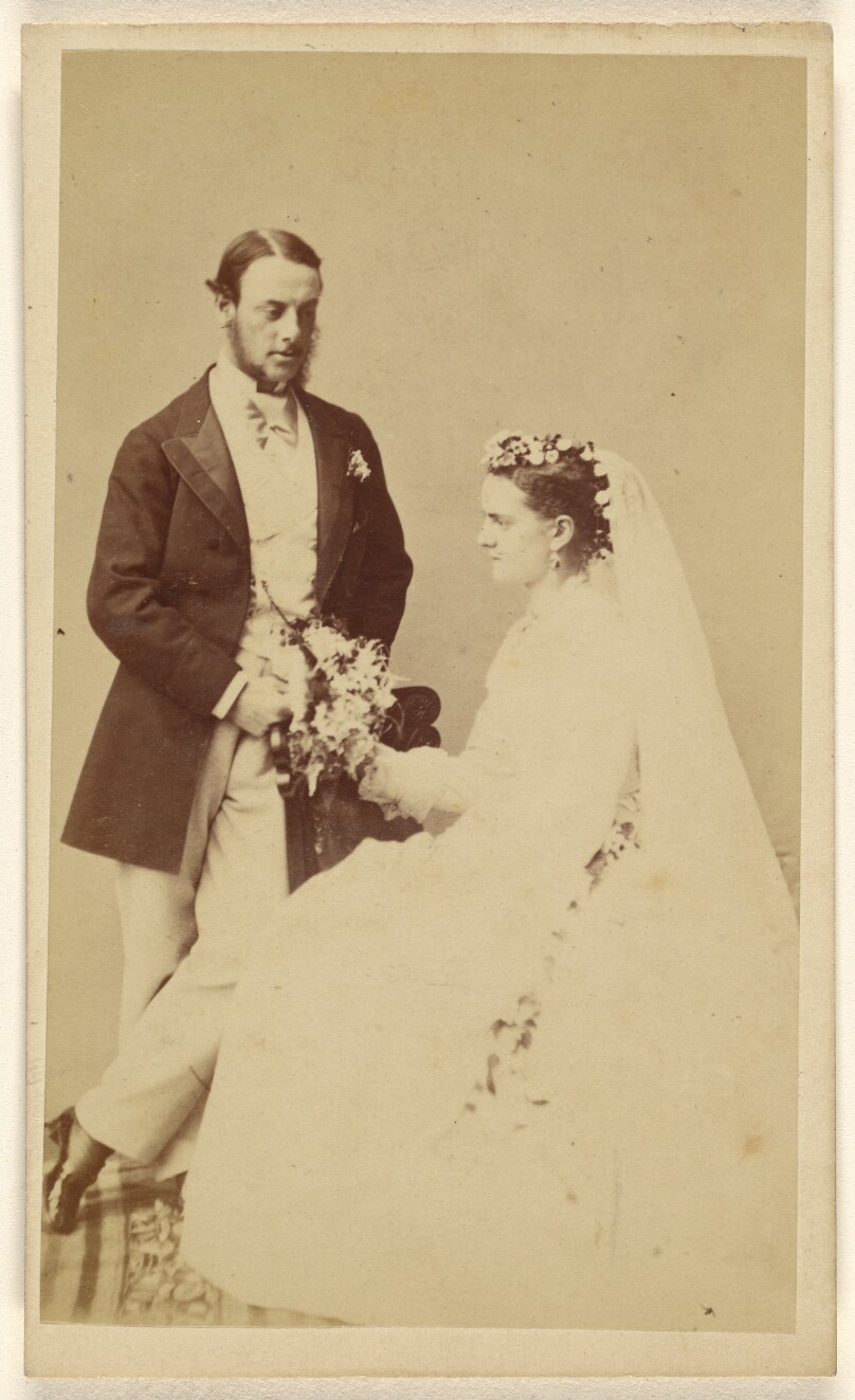 [Unidentified wedding couple: groom standing, bride seated]