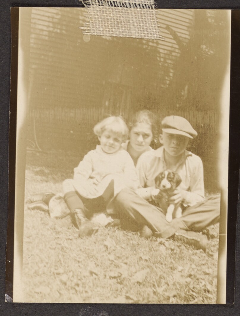 [Three children sit in the grass]