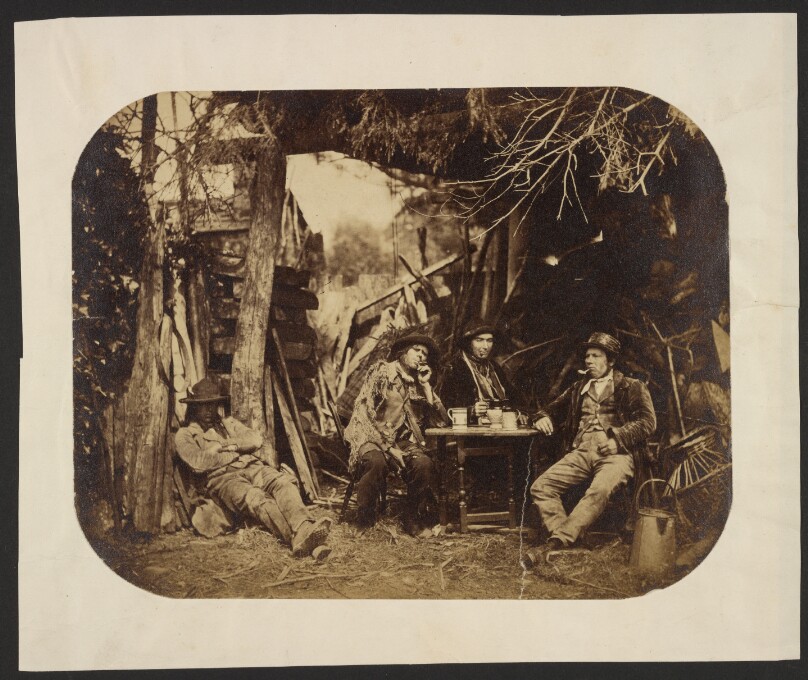 [Men resting around table in a clearing]