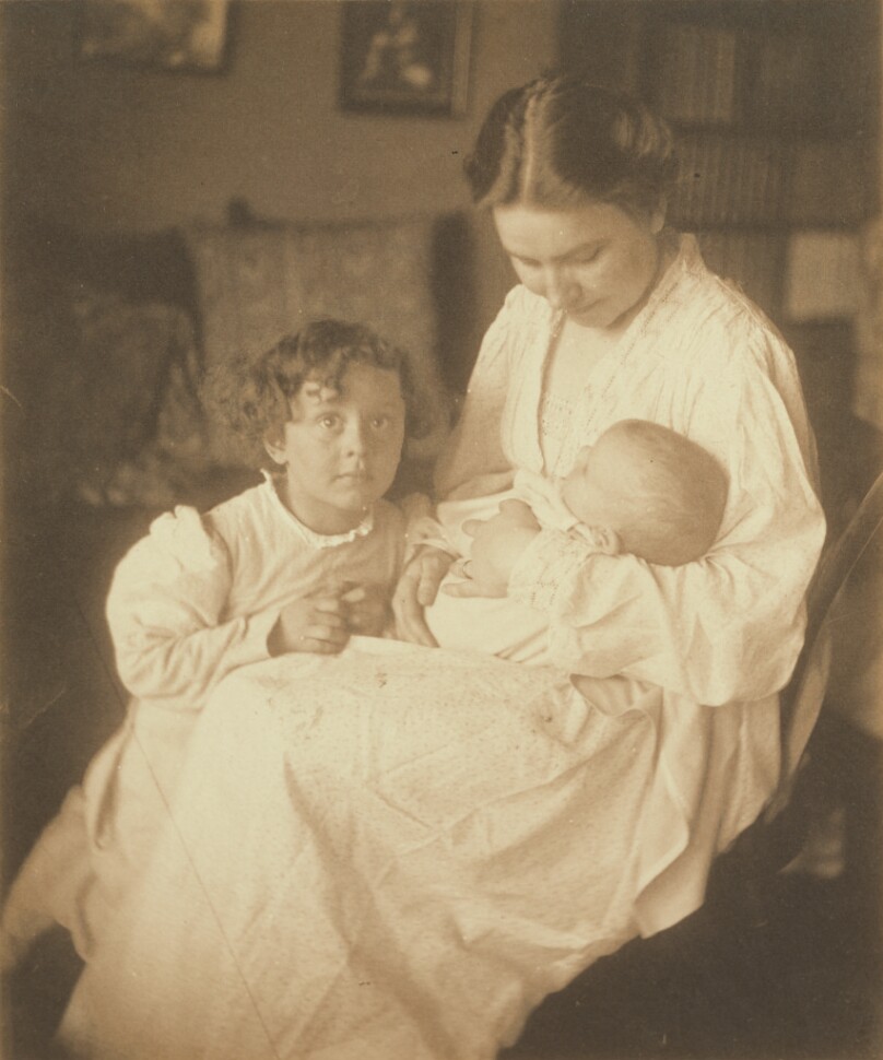 [Mother in dressing gown, seated, with infant and small son]