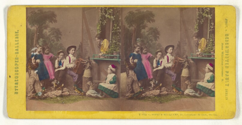 [Group of children in native costume posed in a studio, one boy is playing an accordion, a monkey is on a barrel]