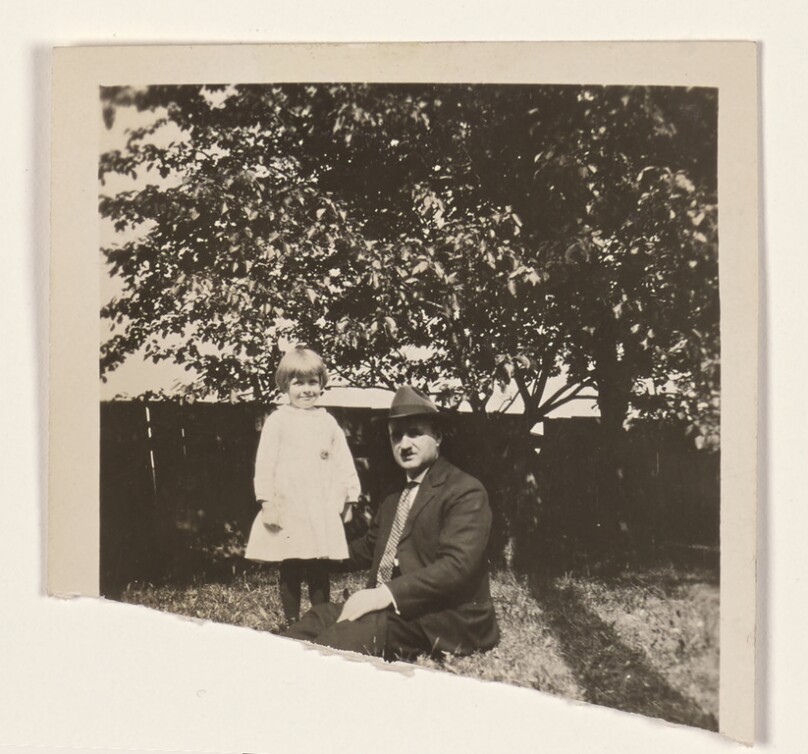 [Man seated on grass with a child]