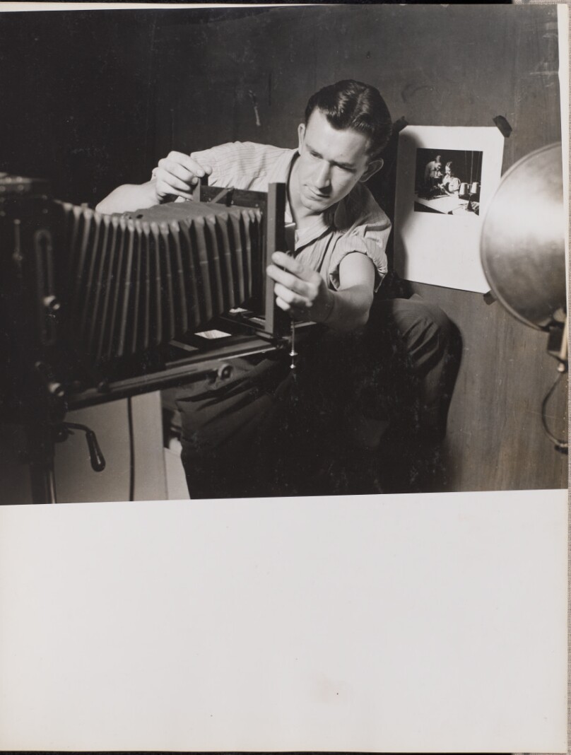[Man adjusts folding bellows on a large-format camera]