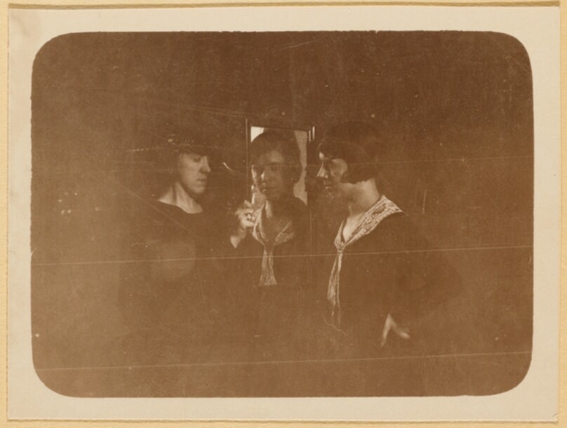 [Three women gathered around flower]