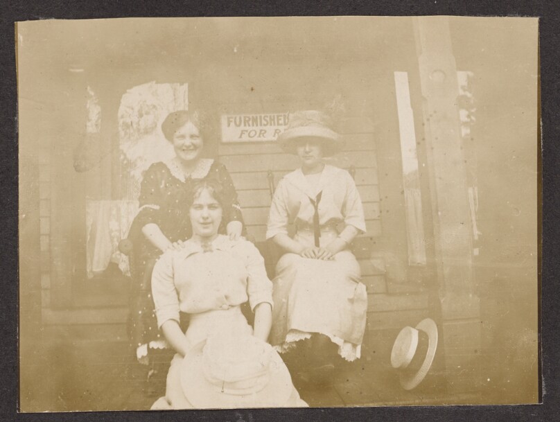 [Three women pose on a porch]