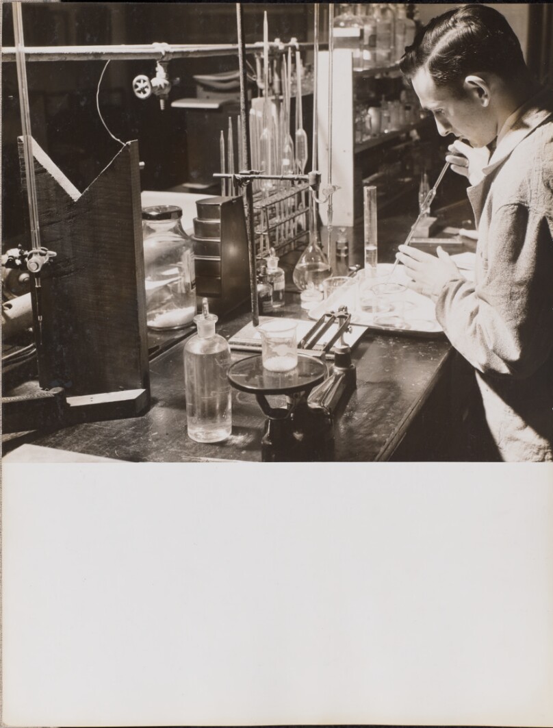 [Man in a lab uses both hands to place a large pipette into a beaker]
