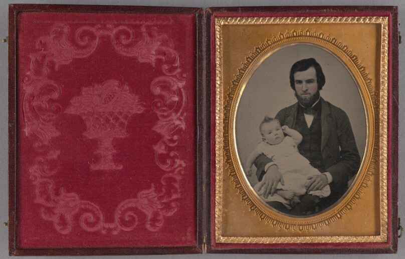 [Portrait of a bearded man seated, holding a baby]