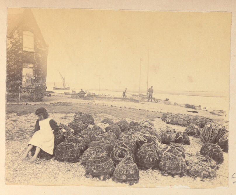 [Girl sitting by fishing baskets]