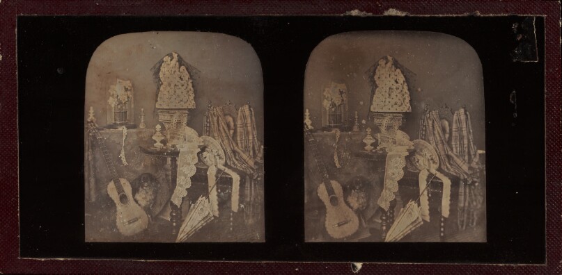 [Still life with guitar, fabrics, umbrella, statuary, and small stuffed dog]