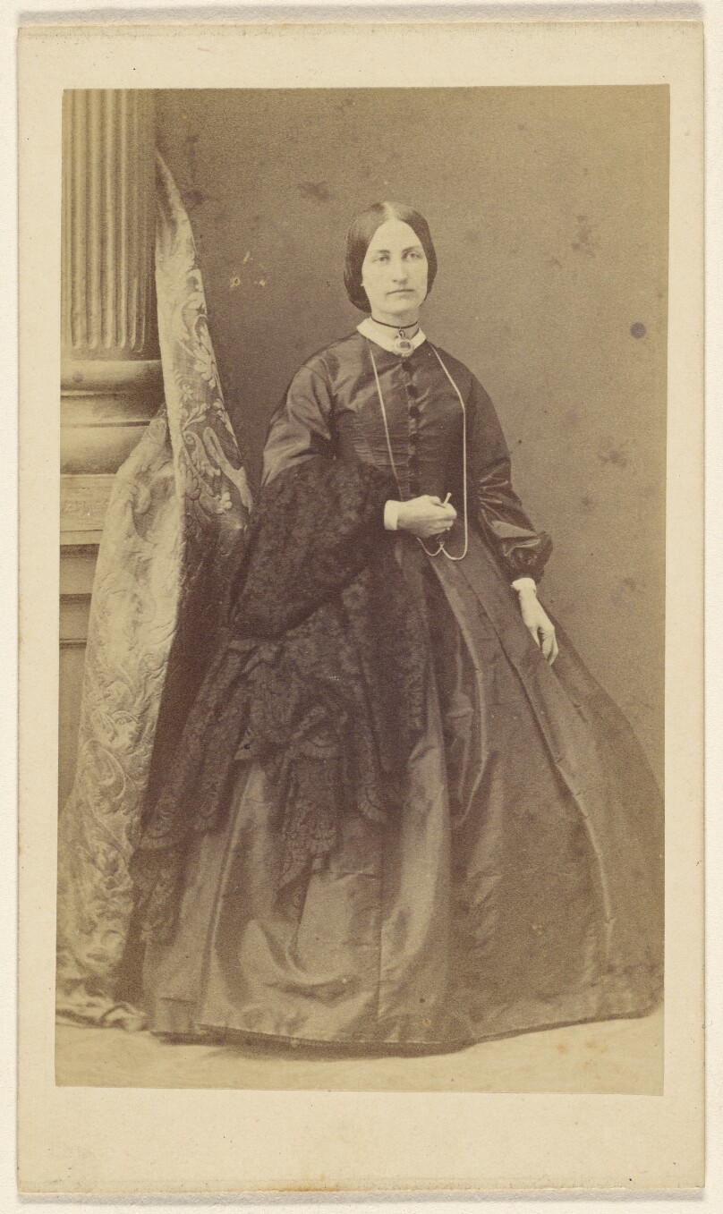 [Unidentified woman in long black dress, standing]