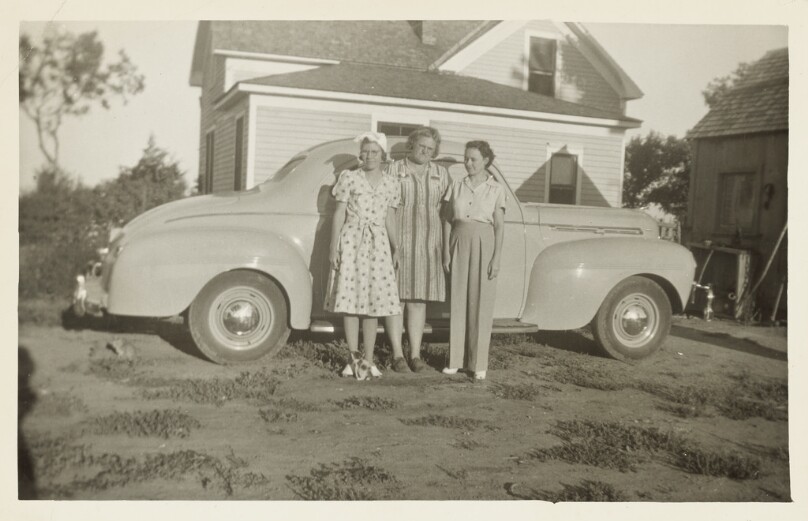 [Three women in front of car]
