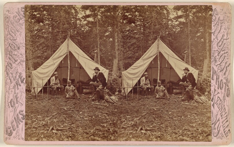 [Group of beared men seated at campsite, tent in background]