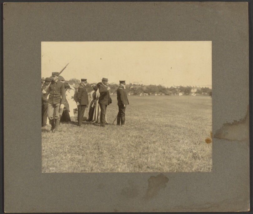 [Soldiers and group of ladies standing at edge of field]