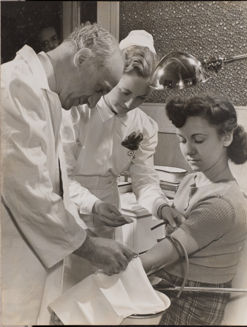 [Doctor and nurse insert a needle into a woman's arm]