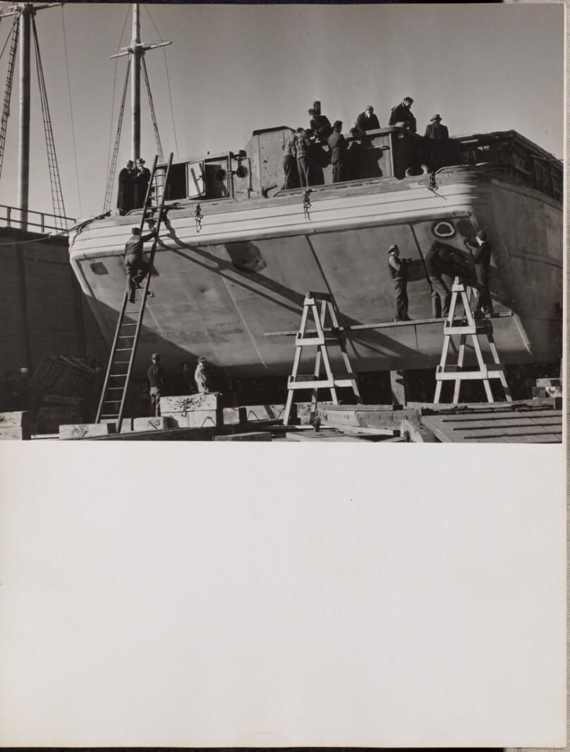 [A group of men work on a docked boat]