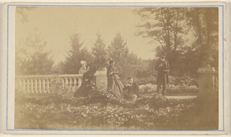 [Five unidentified people: three women and one man standing, one man seated, in a garden]
