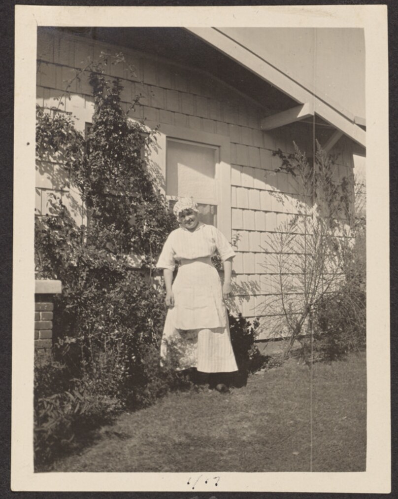 [Woman standing next to a house]