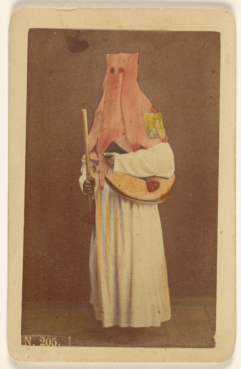 [Unidentified man in long hood holding a candle and book, standing]