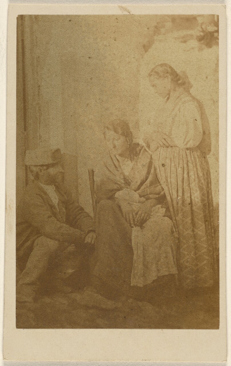 [Woman seated holding a baby, a man and woman on either side]