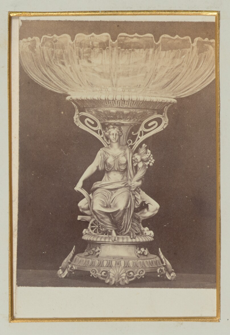 [Ornate glass-top serving dish with a figurine of a woman at the base]