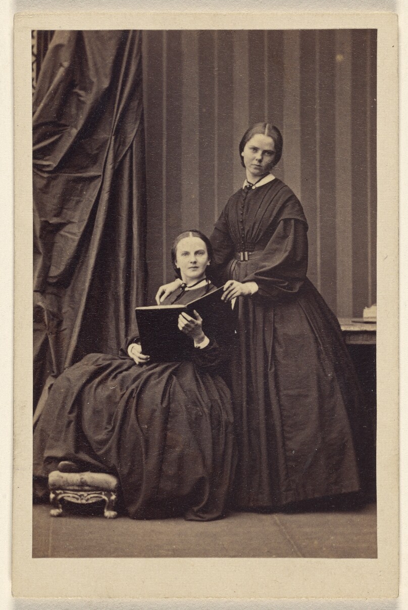 E.J.B. [two unidentified women: one seated, holding a book; one standing]