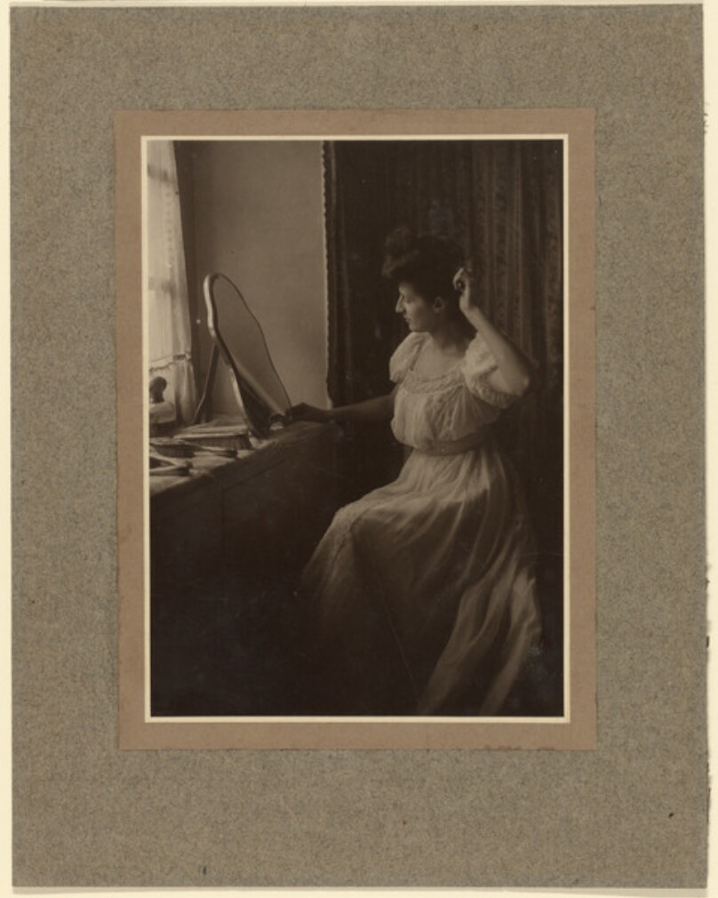 [Woman brushing her hair at vanity]