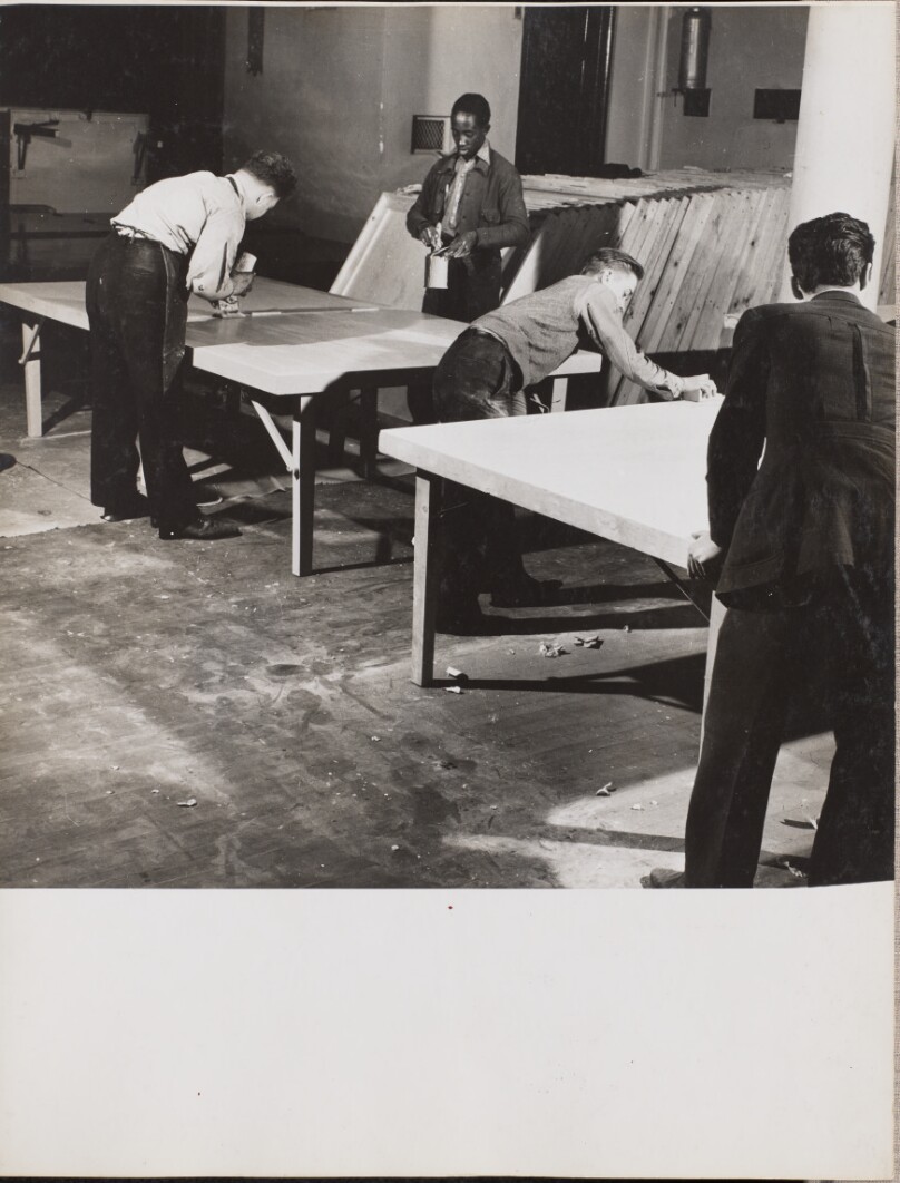[Four men sand and varnish large, wooden boards]