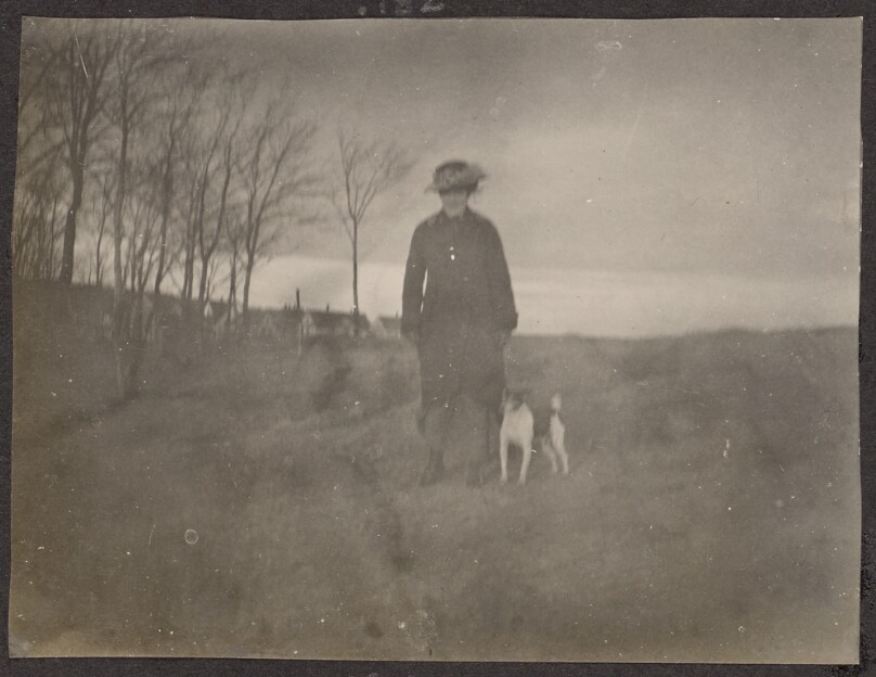 [Woman standing in a field with a dog]