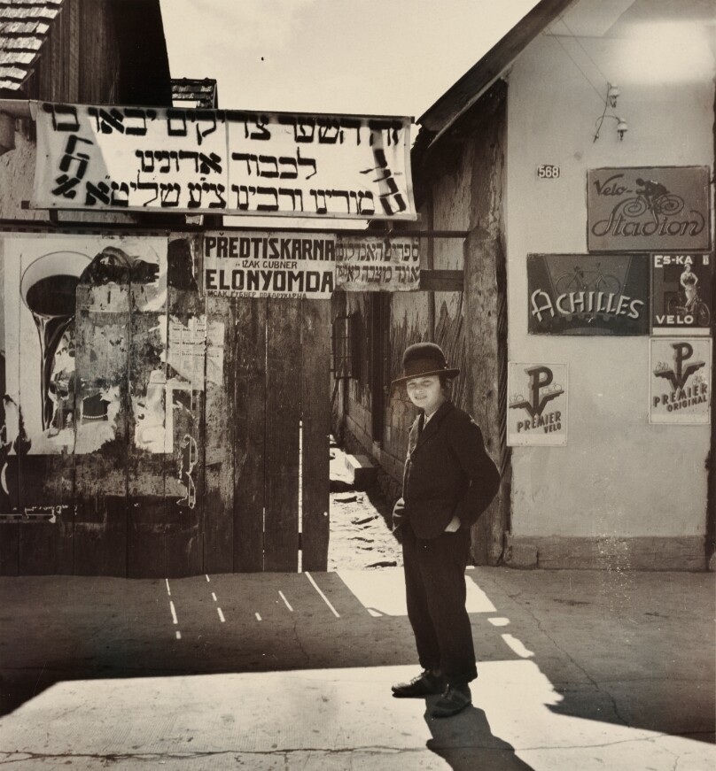 Boy standing in front of a banner that reads, 'This is the gate through which the righteous will come,' Mukacevo, Rachov or Uzhorod