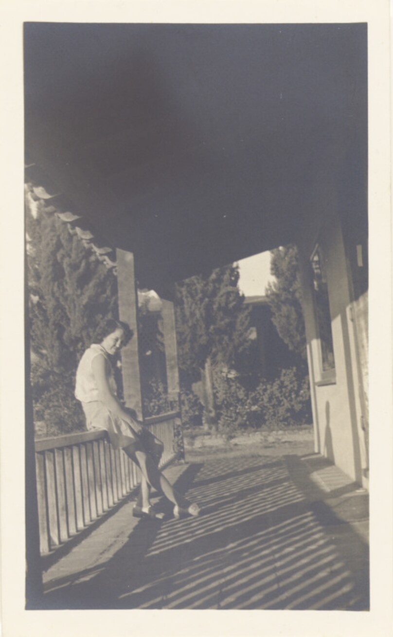 [Woman sitting on porch railing]