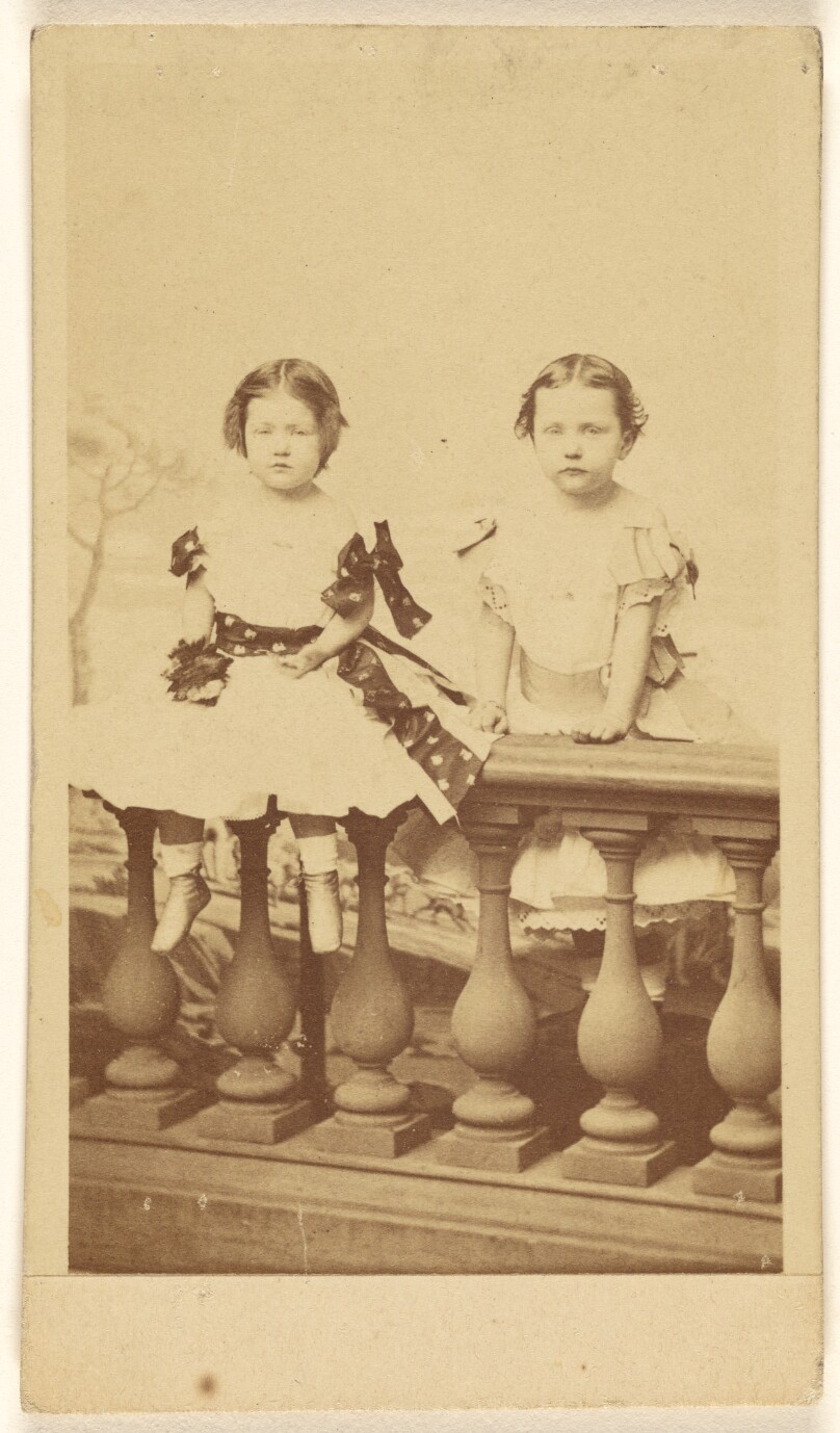 [Two unidentified little girls posed on a railing]